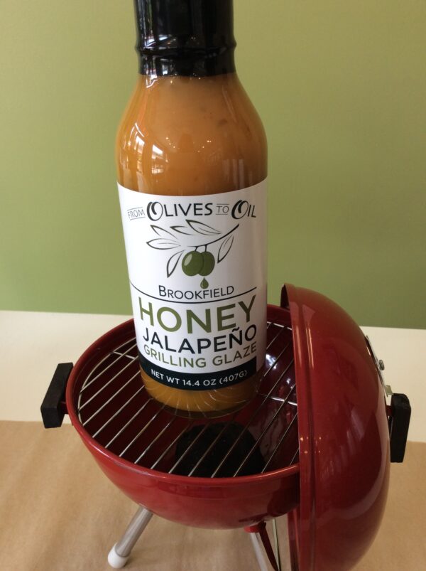 A bottle of honey jalapeno grilling sauce on top of an electric grill.