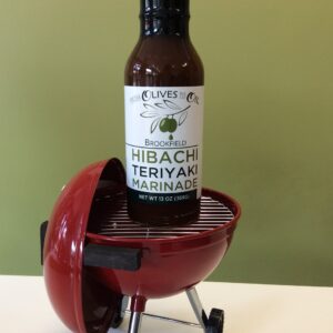 A bottle of sauce is sitting on top of the grill.