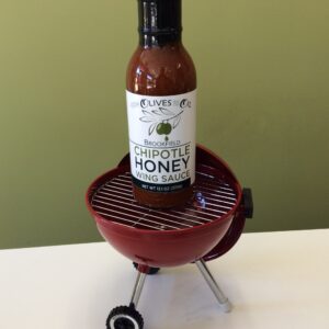 A bottle of chipotle honey sauce on top of an outdoor grill.
