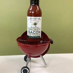 A bottle of smokey bacon ketchup sitting on top of a grill.
